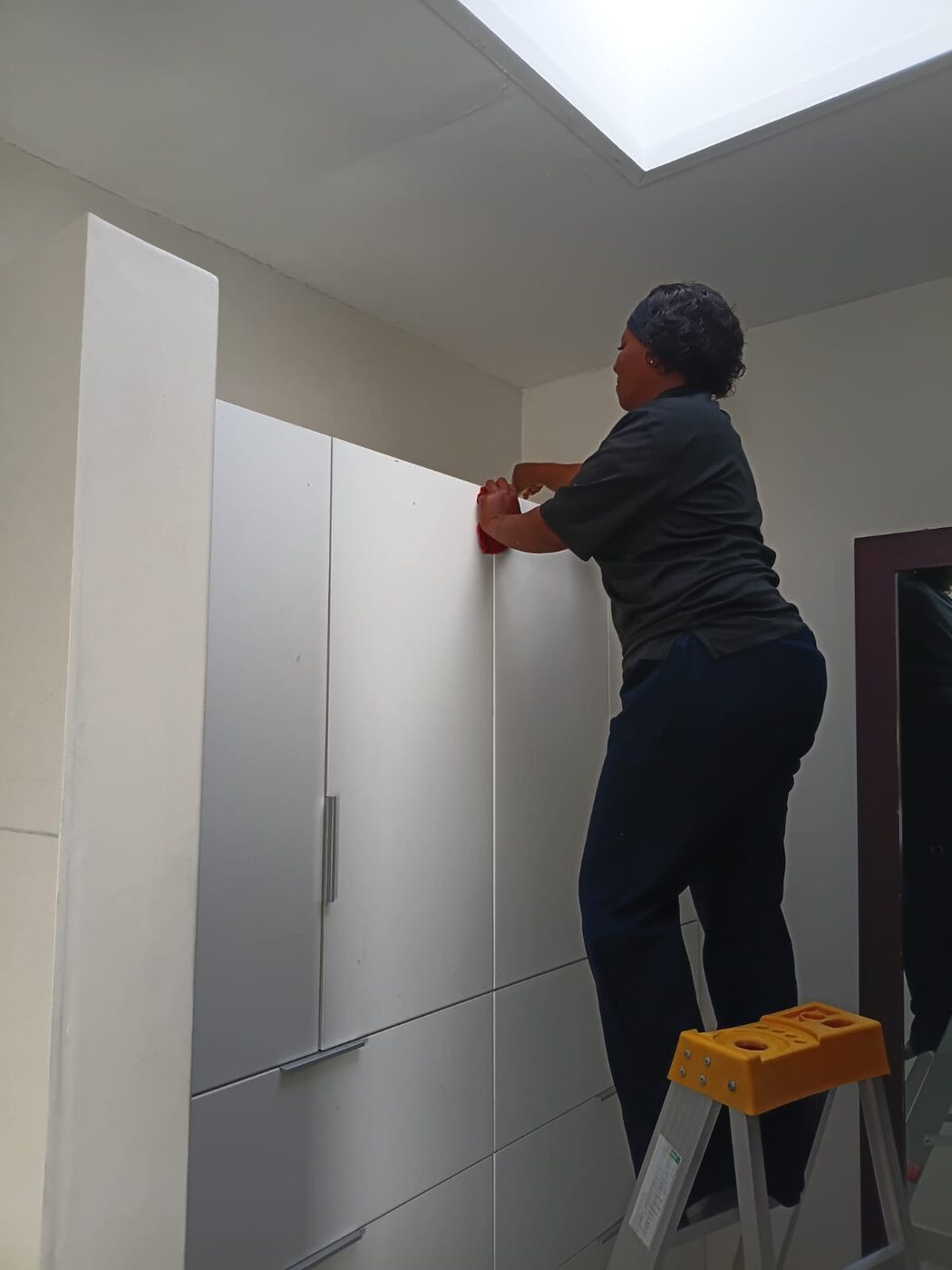Cayroh team member wiping the fronts of built-in cupboards in an empty room