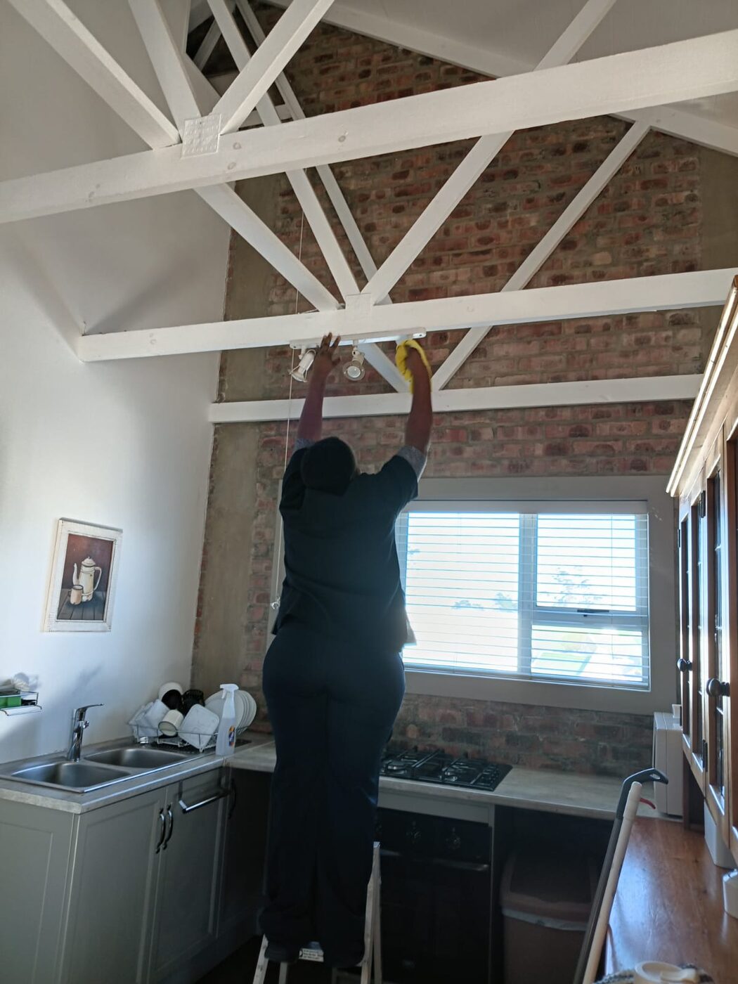 Cayroh team member cleaning a high window below exposed roof trusses